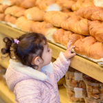 Young girl looking at Challah in a bakery.