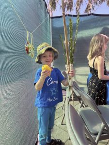 A child with a Lulav (bundle of greens) & Etrog (a type of citrus fruit)